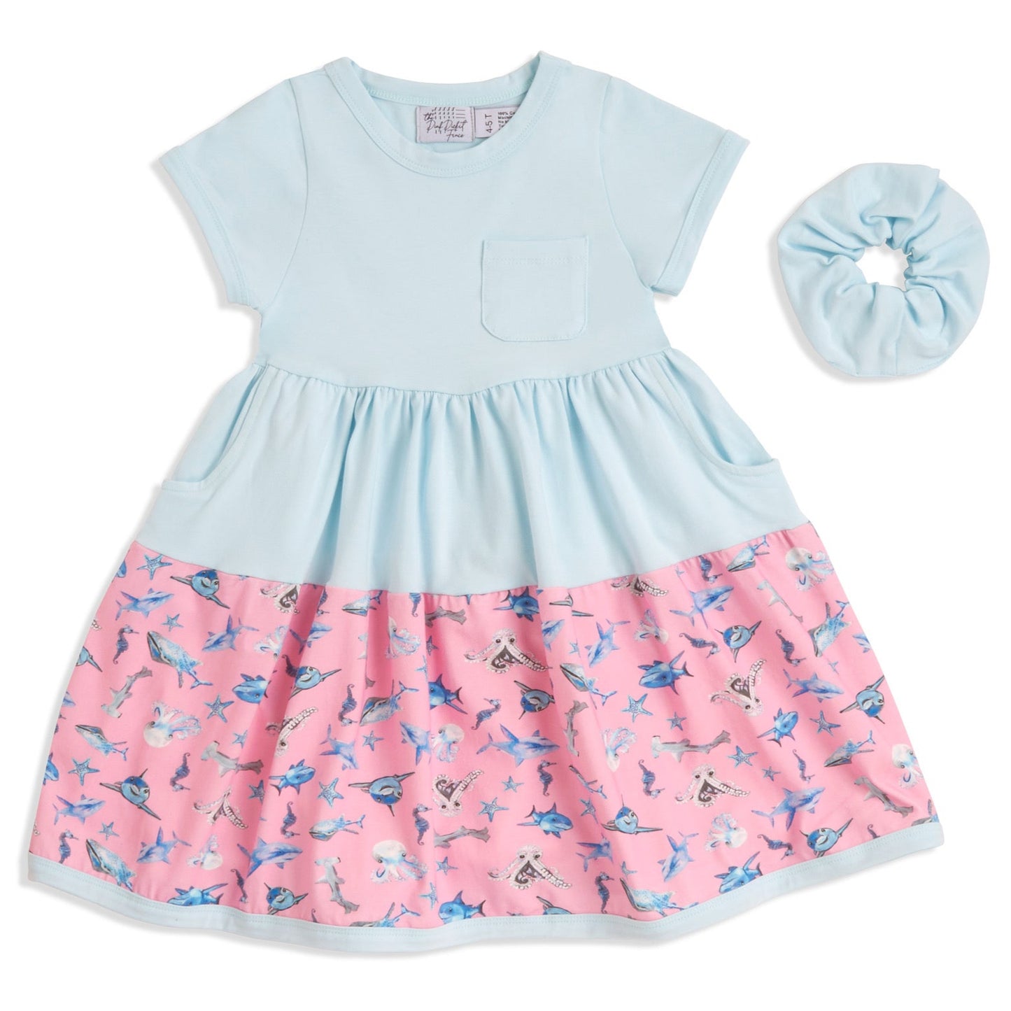 Flat lay of blue Sparky Shark twirl dress with matching scrunchie – girls ocean-themed dress in soft cotton with sharks, whales, and seahorses