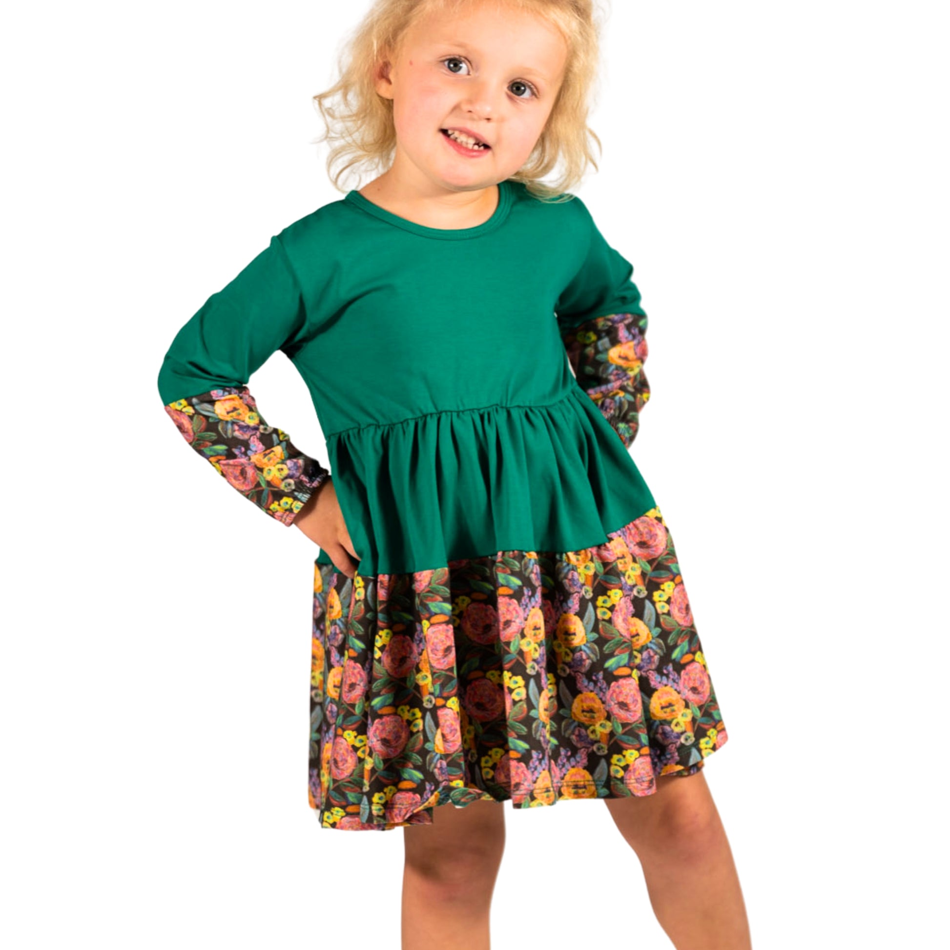Little girl twirling in a green long sleeve cotton dress; twirl-friendly silhouette by The Pink Picket Fence