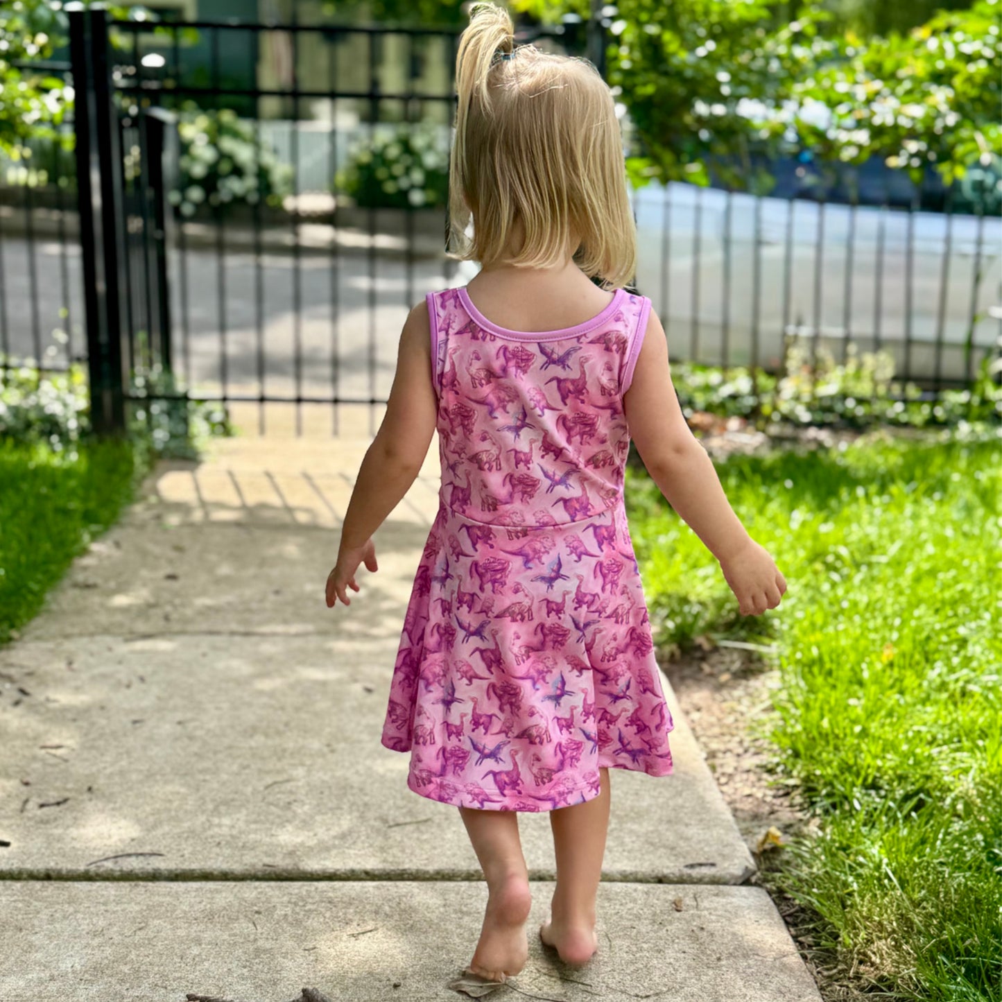 Little girl playing in pink dino-print dress – lightweight and breathable fabric ideal for warm weather