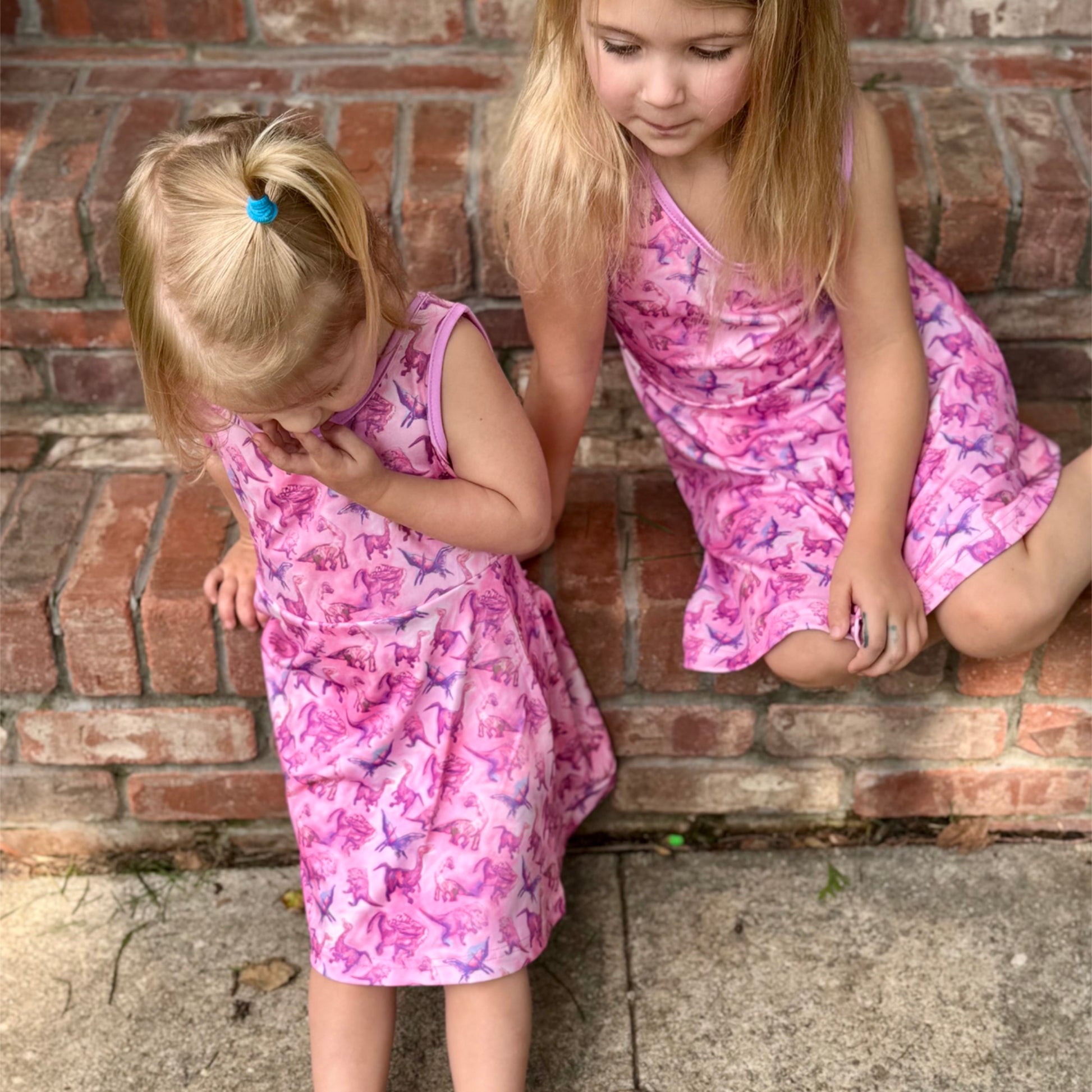 Close-up of girls in Paleontology Pink dino dress showing relaxed fit and stretch fabric for sensory comfort