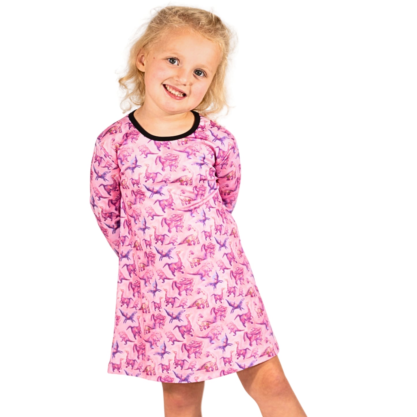 A young girl wearing a long-sleeved pink dinosaur print twirl dress.