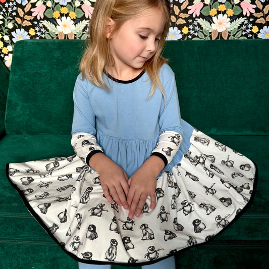 Little Girl in Penguin Outfit - Indoor shot of a girl smiling in her Penny Penguin Dress, designed for comfort and movement