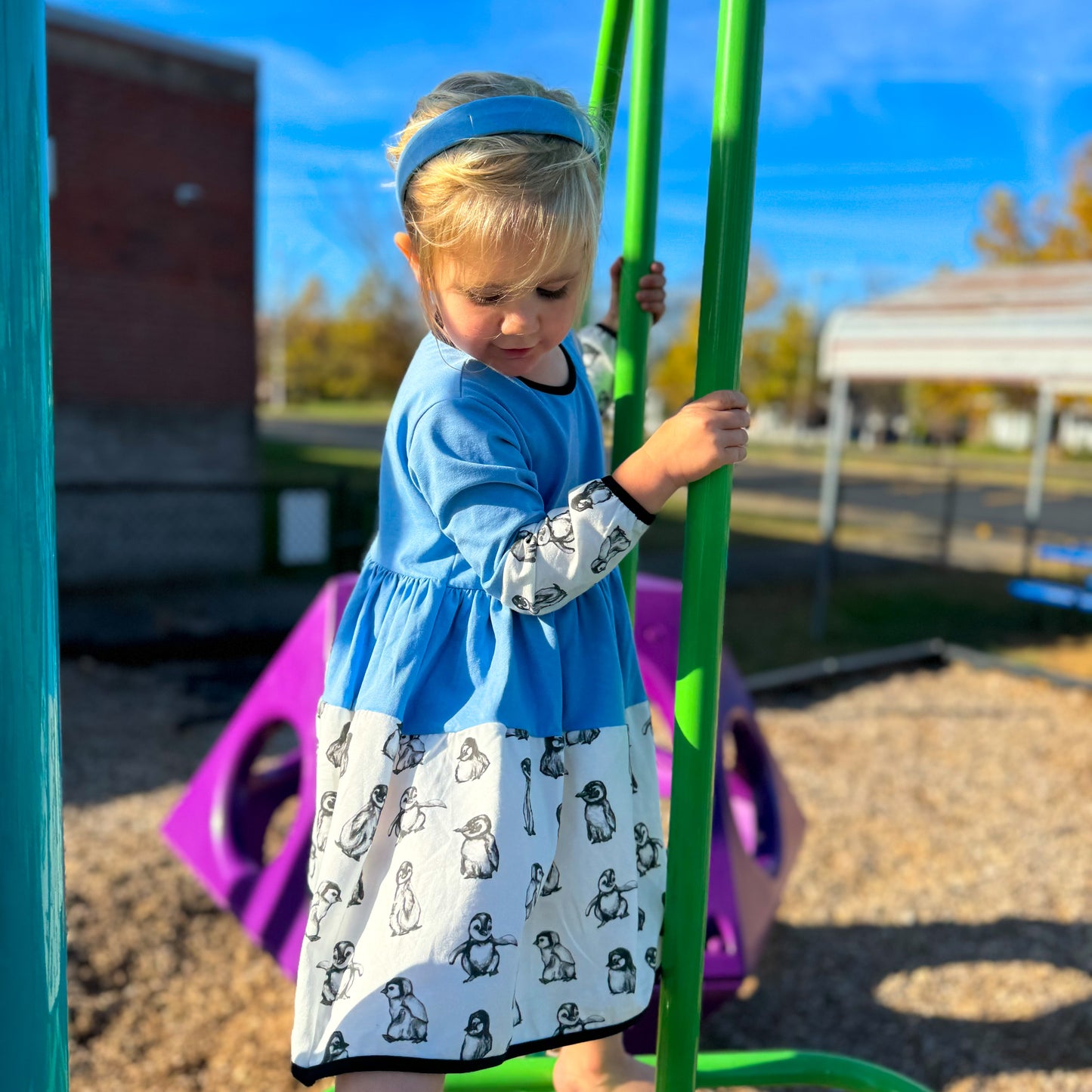 Young Girl Wearing Blue Headband and Penguin Outfit