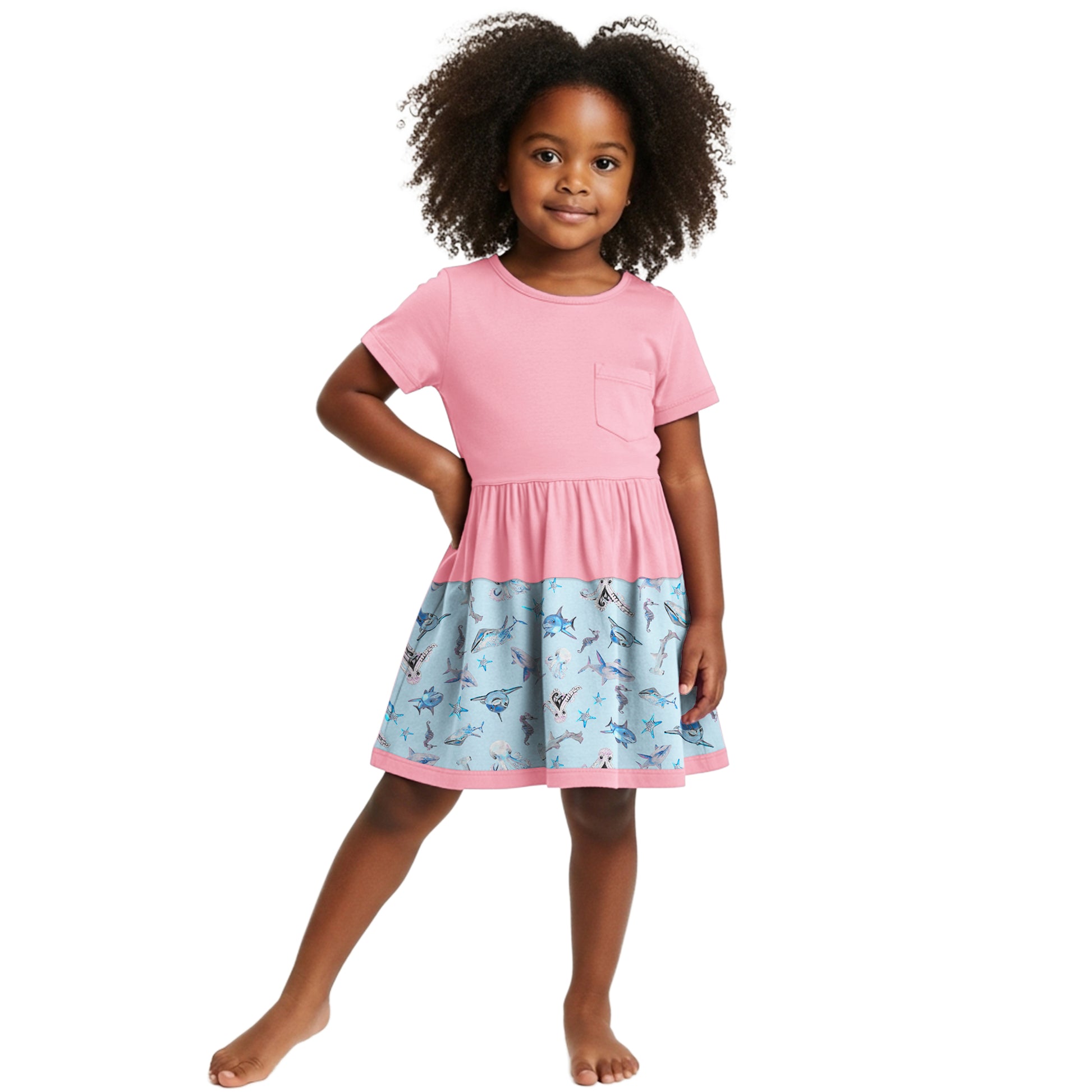 Young girl wearing a pink dress with a patterned bottom half on a white background