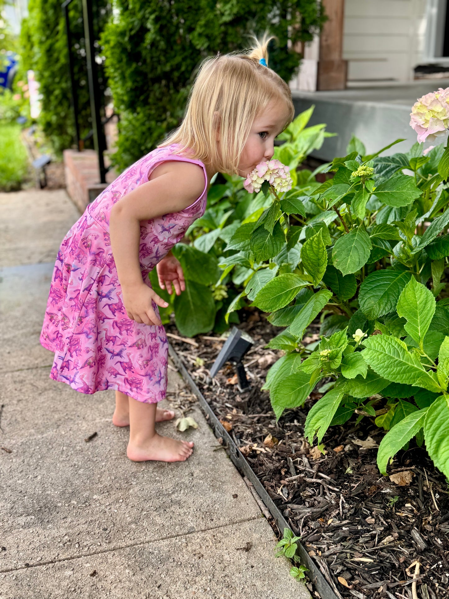 Little girl playing in pink dino-print dress – lightweight and breathable fabric ideal for warm weather
