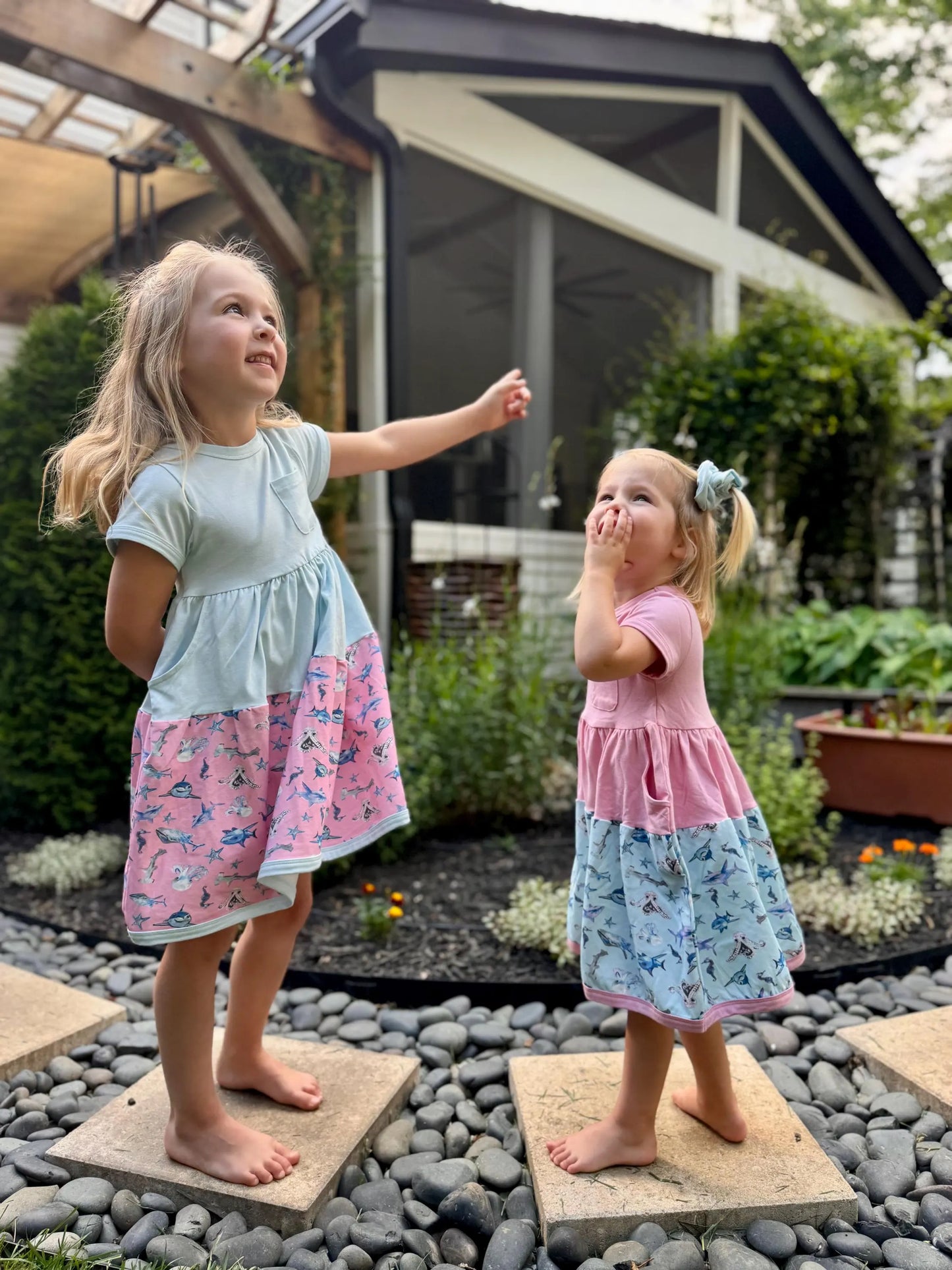 two girls wearing shark and dinosaur twirl dresses standing outdoors soft sensory friendly kids outfits for summer play